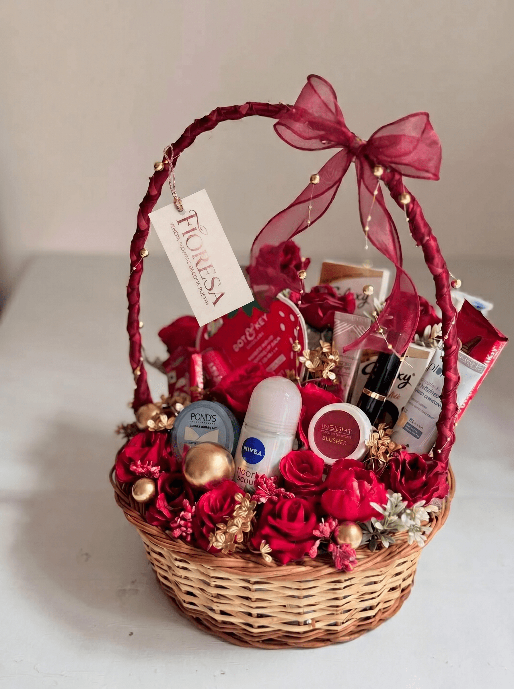 Front view of a Fioresa beauty and self-care hamper with POND'S, NIVEA, INSIGHT blusher, Dot & Key and red roses.