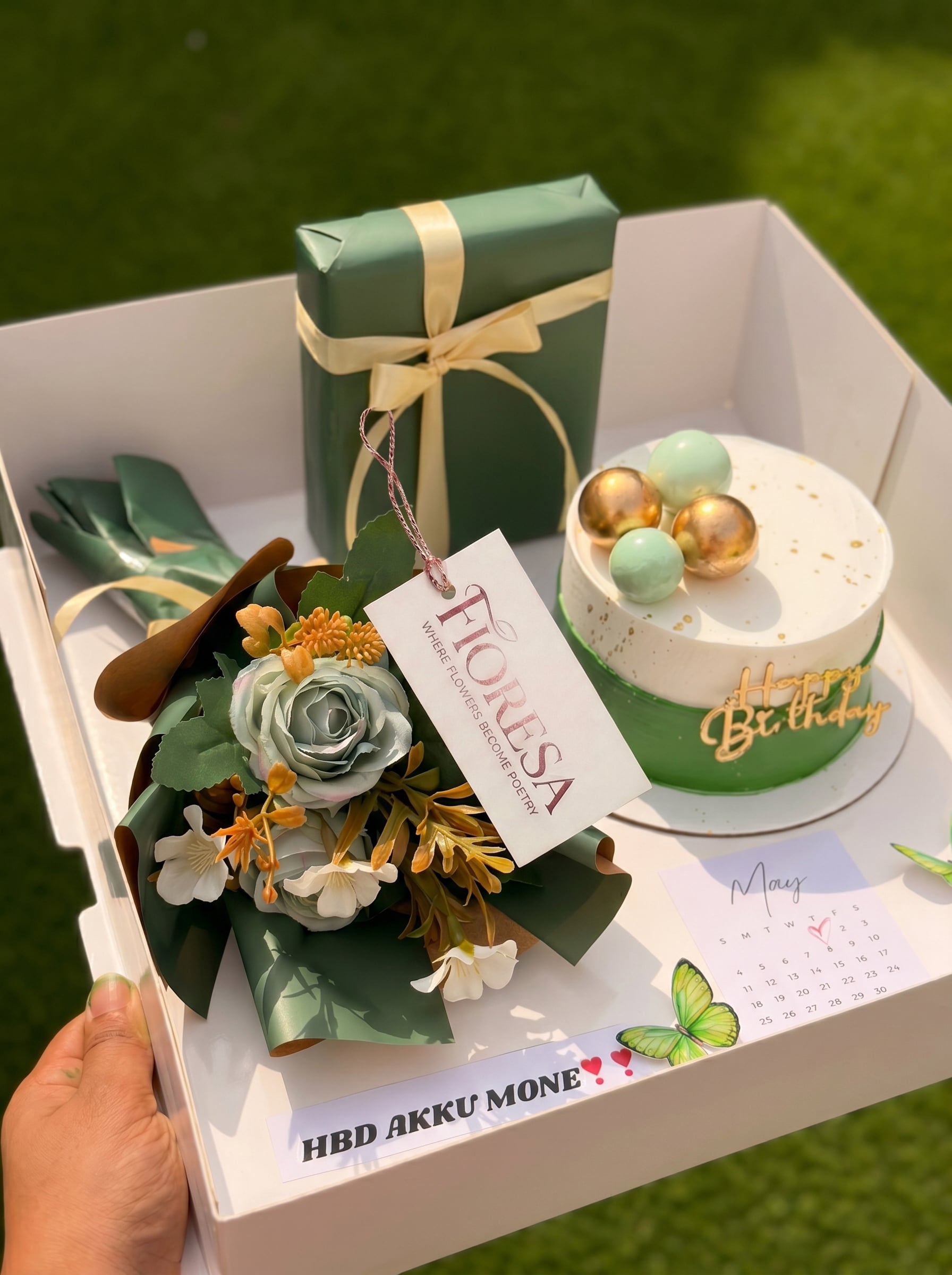 A luxury Fioresa gift hamper featuring a green birthday cake, matching bouquet, and wrapped gift.